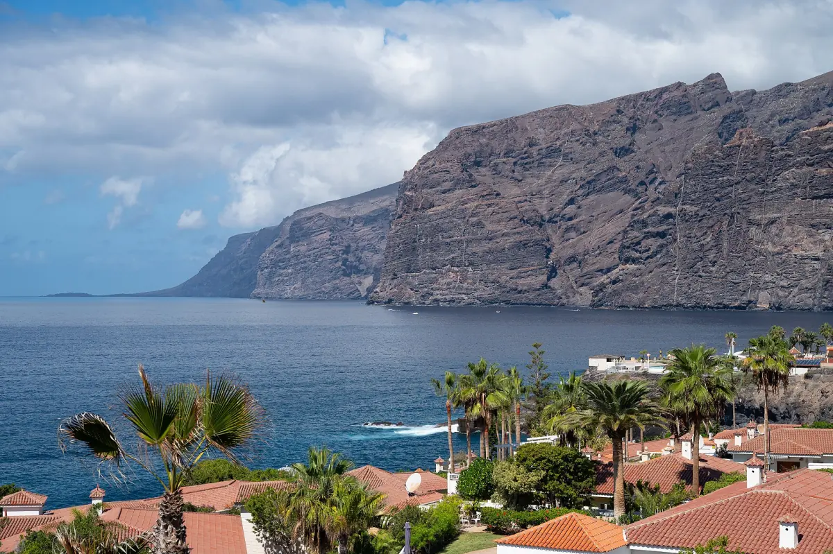 Die Klippen von Los Gigantes über dem Meer, gesehen über Palmen und Dächer